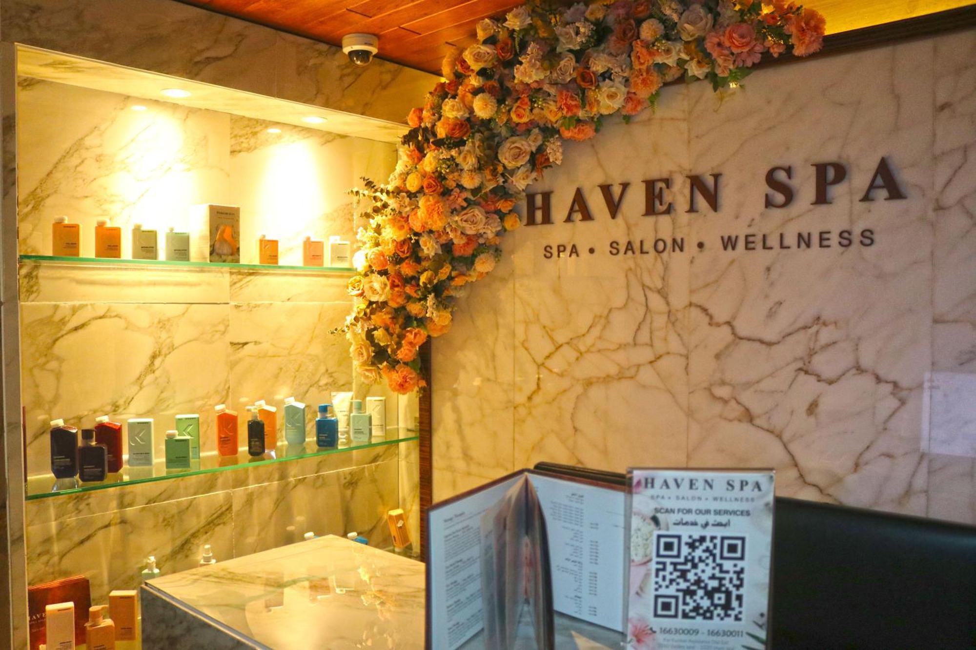 Lagoona Beach Luxury Resort And Spa Manama Exteriör bild The photo shows the interior of a spa called "Haven Spa." The wall is decorated with beautiful artificial flowers, creating an inviting atmosphere. There are several shelves displaying various colorful bottles and products, likely for skincare or wel