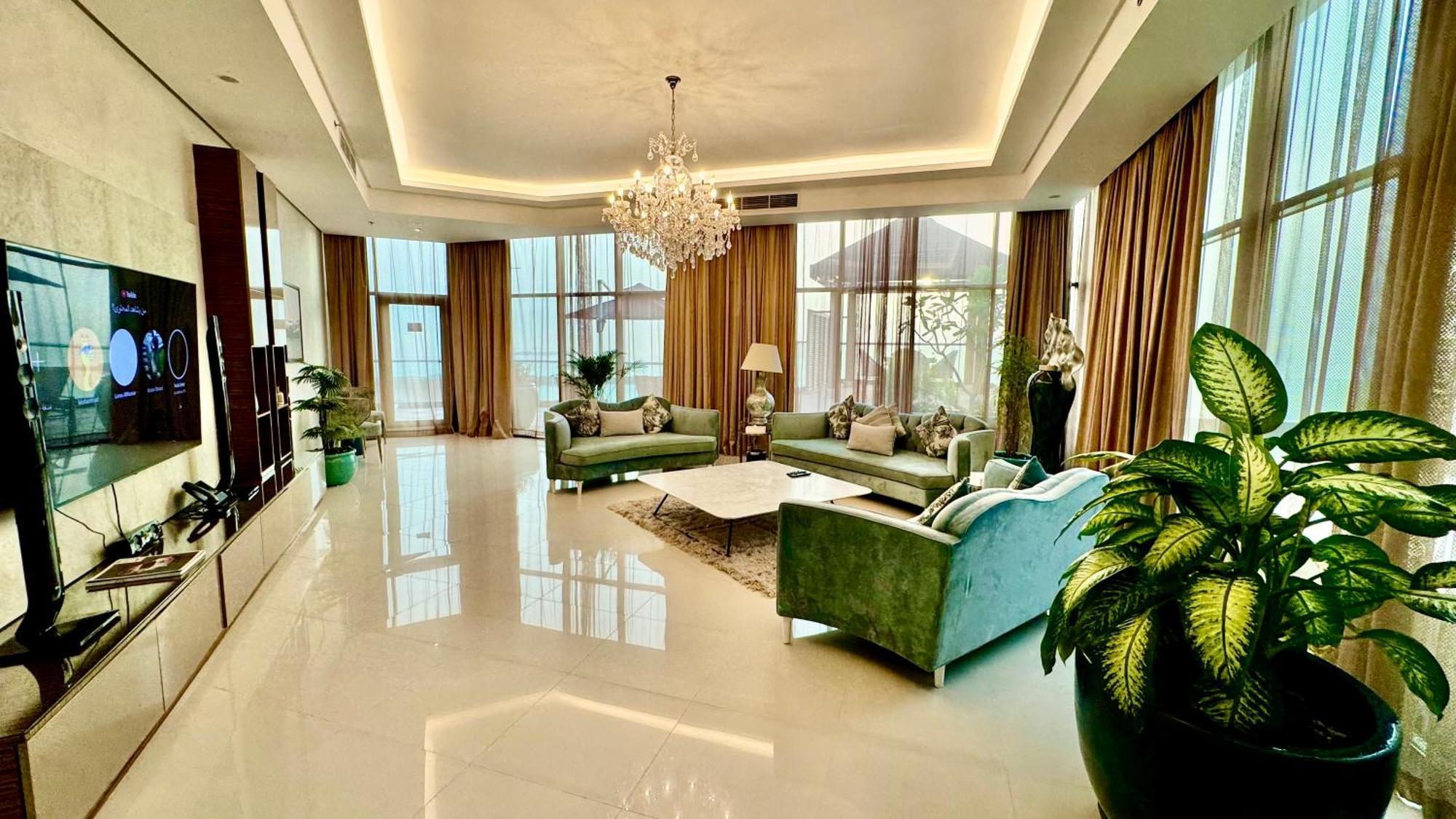 Lagoona Beach Luxury Resort And Spa Manama Exteriör bild The photo depicts a spacious and elegantly designed living room. The room features large windows allowing natural light to flood in, accompanied by sumptuous curtains. The furniture includes a pair of soft green sofas and a centerpiece coffee table s