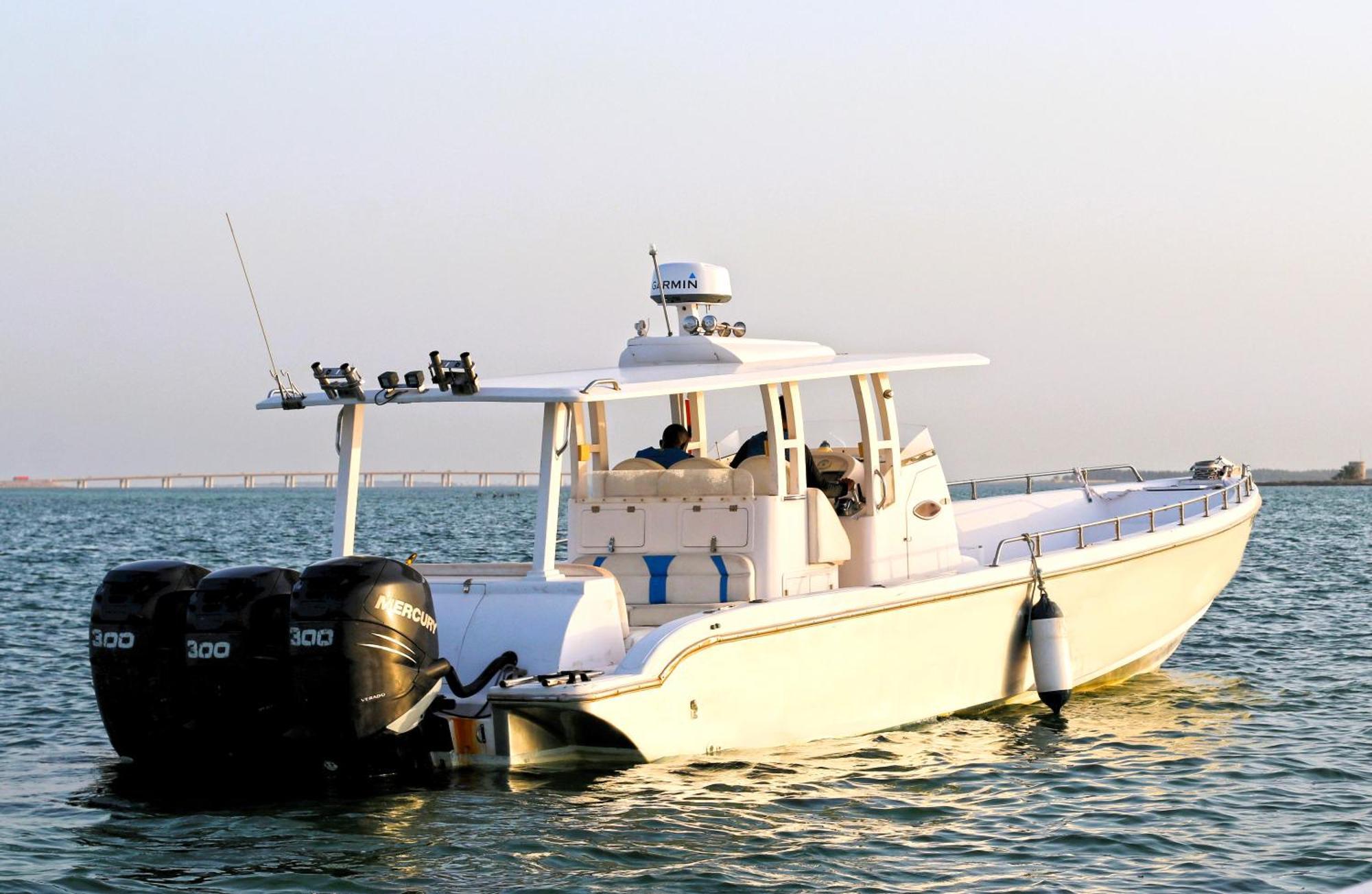 Lagoona Beach Luxury Resort And Spa Manama Exteriör bild The photo shows a large, white motorboat equipped with three powerful outboard engines at the stern. The boat has a sleek design, with a spacious open deck and a covered cabin area that likely provides shelter and controls for navigation. The scene i