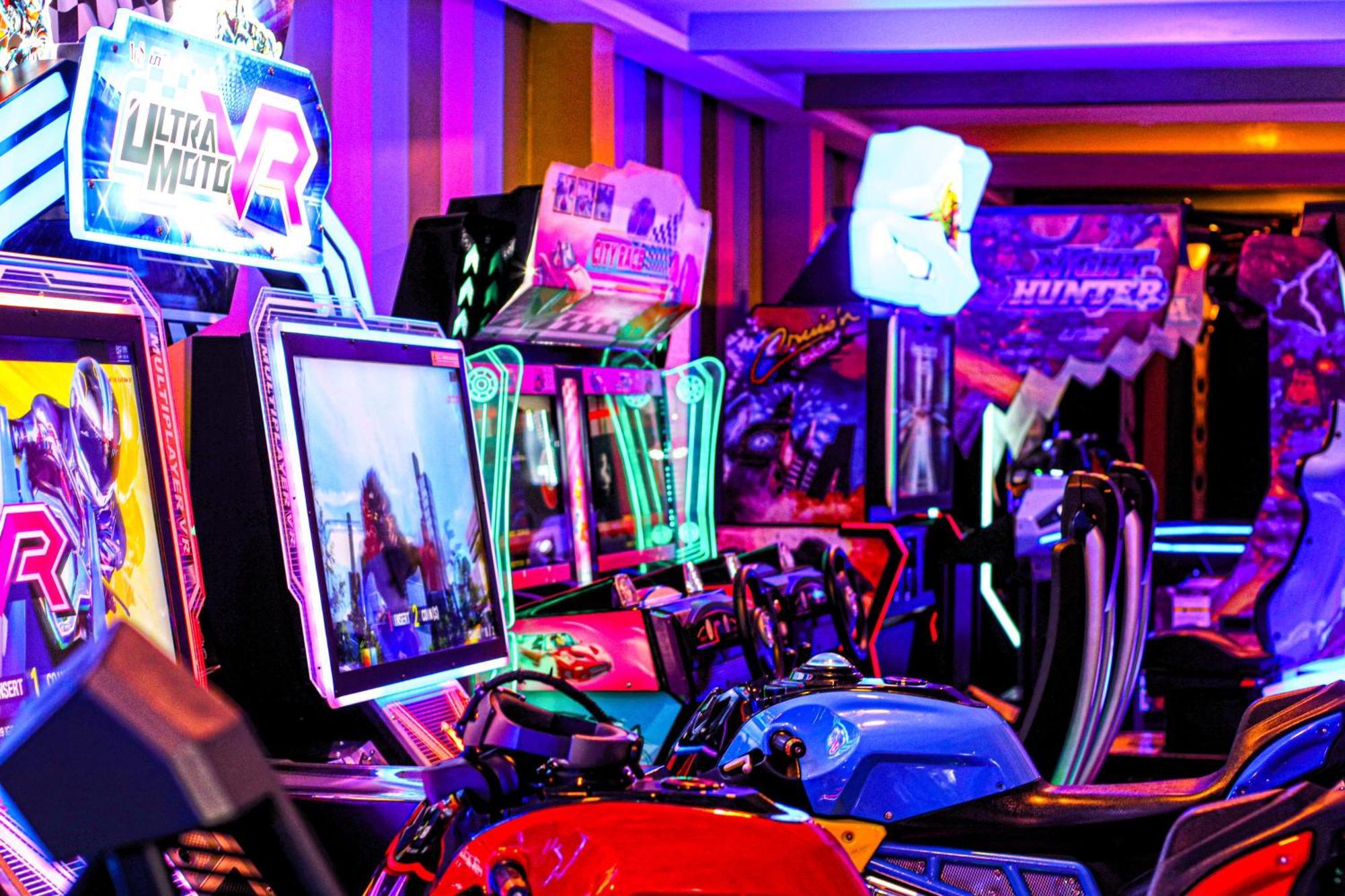 Lagoona Beach Luxury Resort And Spa Manama Exteriör bild The photo shows a vibrant arcade scene featuring various arcade gaming machines. The machines are lined up, showcasing colorful screens and bright, neon lights, creating an energetic atmosphere. Some machines appear to be racing games, as indicated b