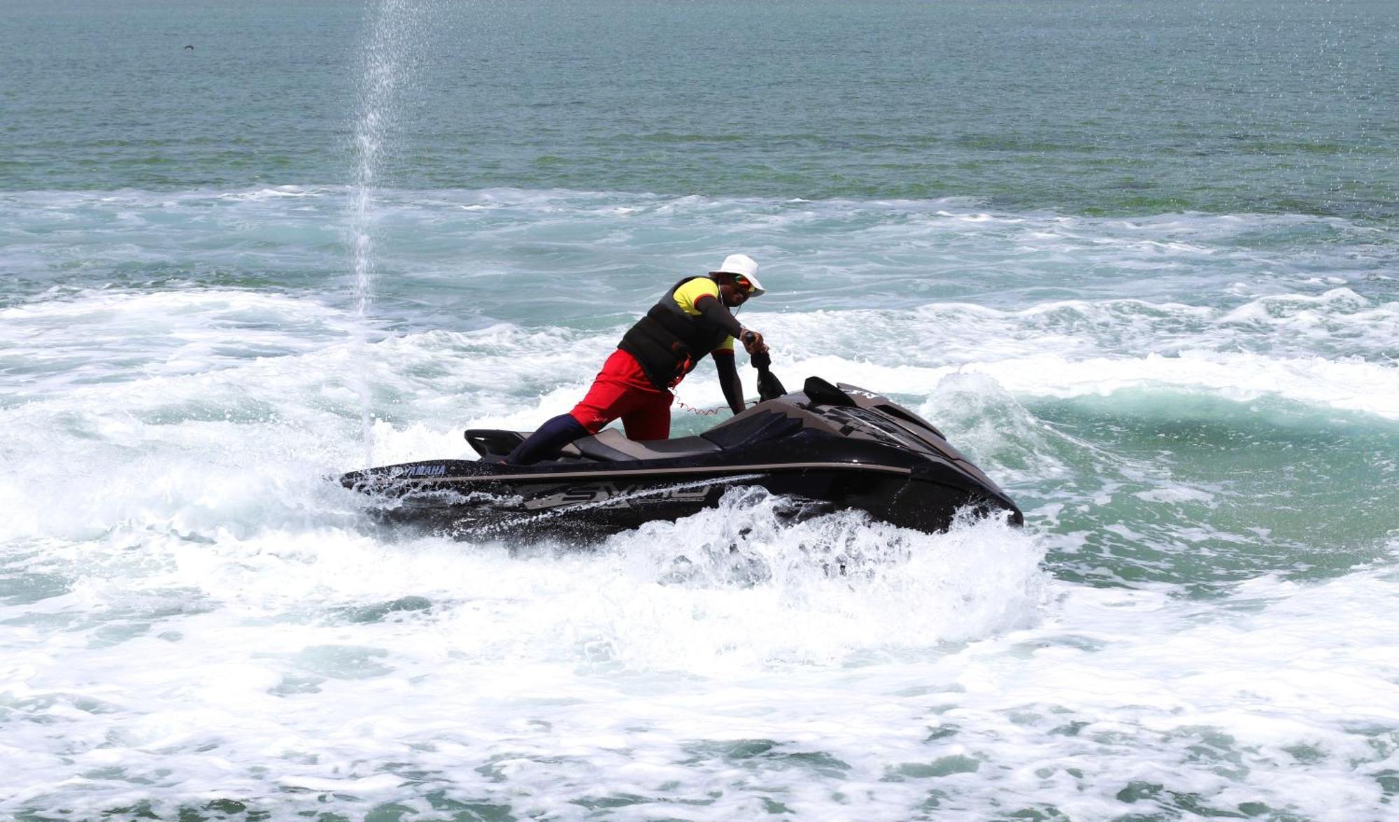 Lagoona Beach Luxury Resort And Spa Manama Exteriör bild The photo shows a person riding a jet ski on the water. The rider is positioned upright, leaning forward with one hand on the handlebars, while the jet ski creates splashes of white foam around it. The water appears choppy, likely due to the motion o