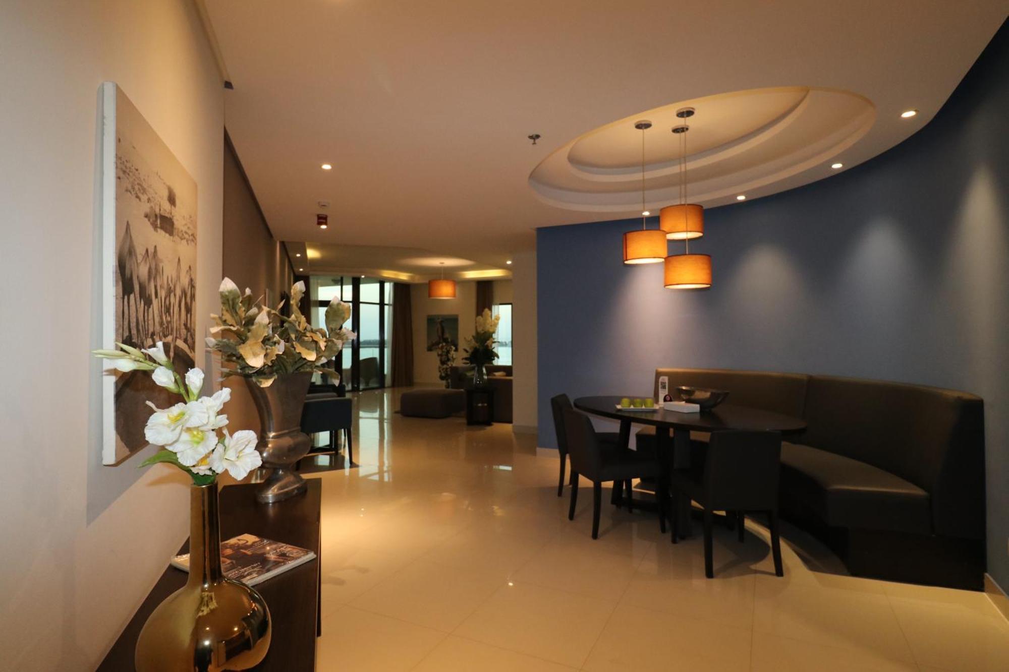 Lagoona Beach Luxury Resort And Spa Manama Exteriör bild The photo showcases an interior space, likely a modern lounge or reception area. It features a combination of soft lighting, neutral-colored walls, and decorative elements. There are elegant light fixtures hanging from the ceiling, and a curved blue 